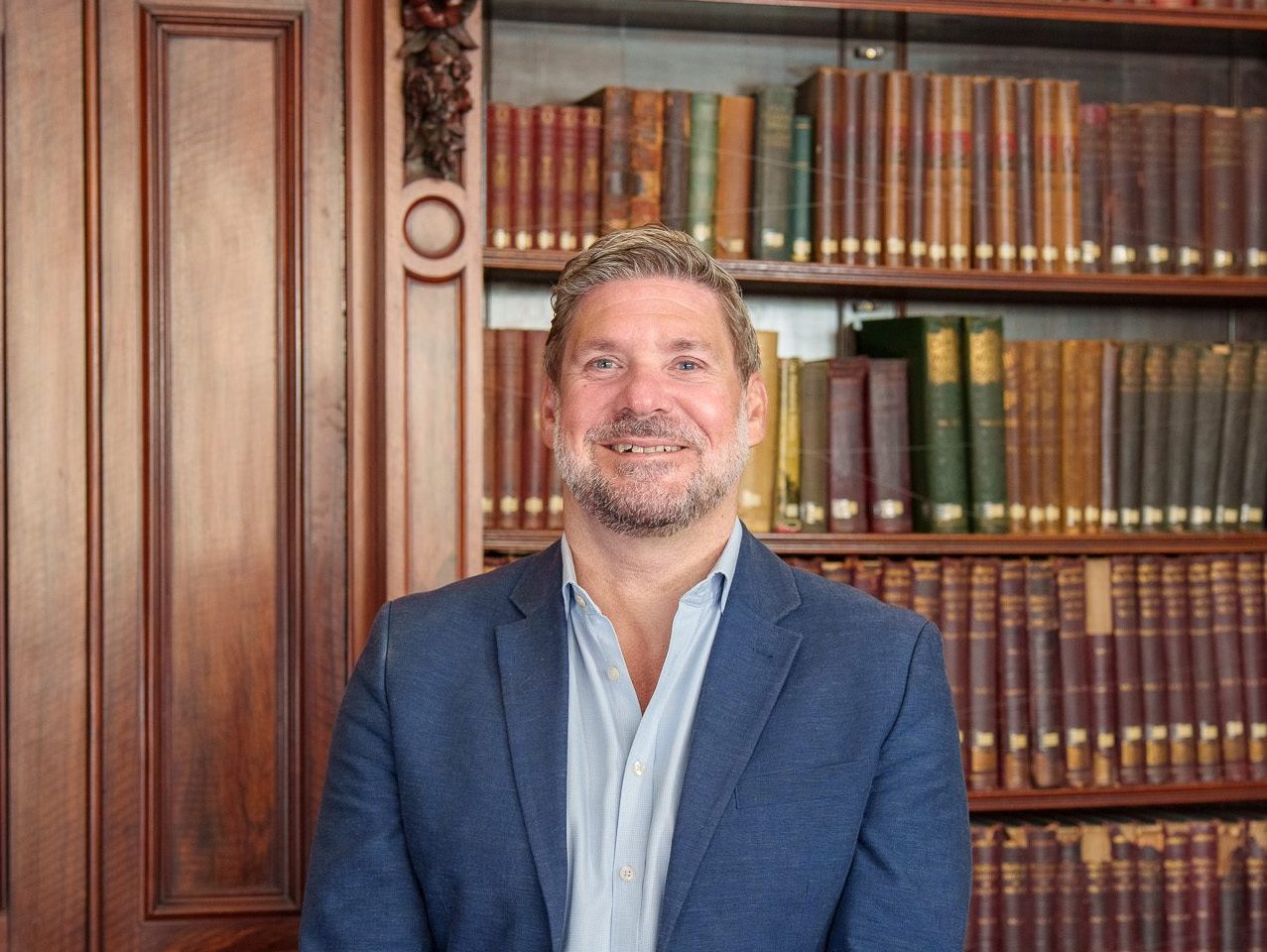 David Goodacre standing in front of the library books in the Members' Library