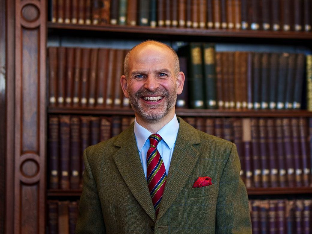 Dave Hill standing in front of the library books in the Members' Library